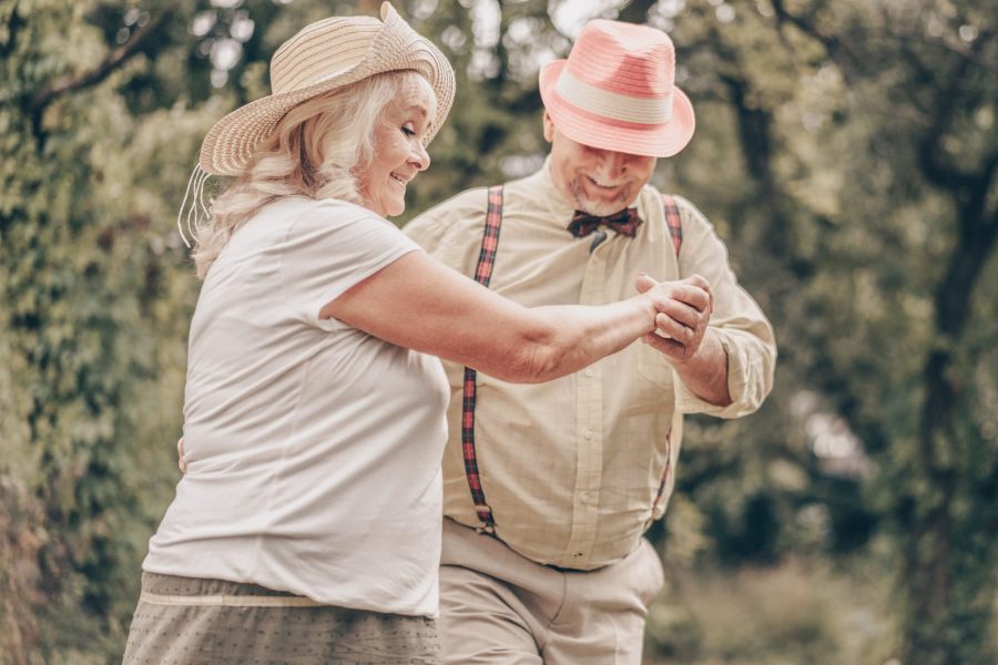 Portrait of an old woman who happily looks at the grandfather with his eyes and smiles at him. Happy couple dancing in the park and remembering youth